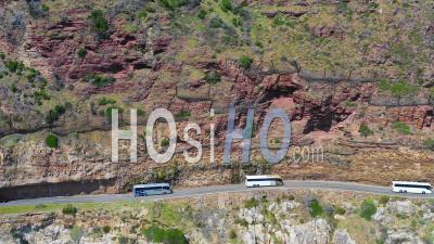 Aerial View Of A Convoy Of Busses Traveling On A Dangerous Narrow Mountain Road Along The Ocean, Chapmans Peak Road Near Cape Town South Africa - Vidéo Drone