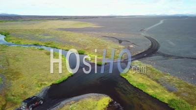 Aerial View Over A Black Van Driving Through A River In The Highlands Of Iceland - Video Drone Footage