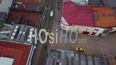 Vue Aérienne, Regardant Vers Le Bas Sur Un Taxi, Une Moto Et Une Voiture Conduisant Dans Les Rues De Bogota, Colombie - Vidéo Drone