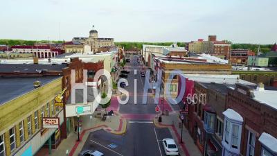 Aerial View Over A Main Street In Small Town Usa Ends With Two Kids Skateboarding Down The Empty Boulevard - Video Drone Footage
