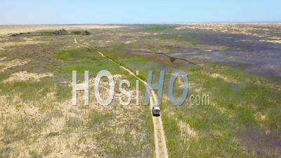 Aerial View Of A 4wd Jeep Vehicle Driving Through A Grassy Or Marsh Area On Safari In Namibia, Africa - Video Drone Footage