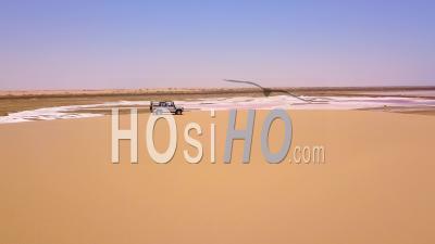 Aerial View Over A 4wd Safari Vehicle Driving On A Colorful Pink Salt Flat Region In Namibia, Africa - Video Drone Footage