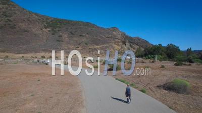Aerial View Following A Man Riding An Electric Unicycle Down A Road In California - Video Drone Footage