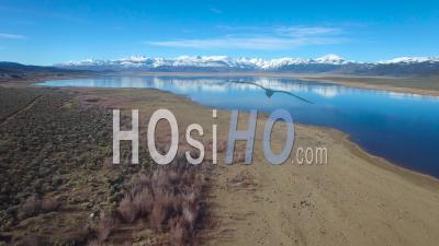 Aerial View Over A Mountain Lake Reveals The Sierra Nevada Mountains In Winter With Plentiful Water - Video Drone Footage