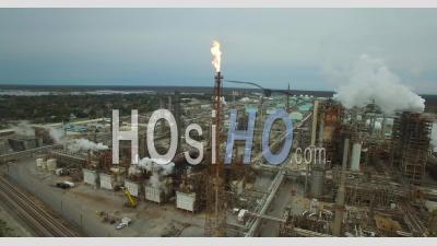 Aerial View Over Huge Industrial Oil Refinery With Gas Torch Burning - Video Drone Footage