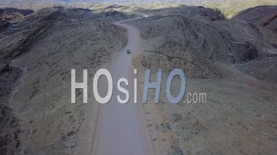 Aerial View Of A 4x4 Jeep Safari Vehicle On A Dirt Road Through The Mountains Of The Namib Desert In Namibia, Africa - Video Drone Footage
