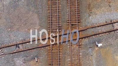 Aerial View Over A Railroad Track Intersection With A Freight Train Passing Underneath - Video Drone Footage