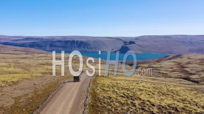 Aerial View Over A Black Camper Van Traveling On A Dirt Road In Iceland In The Northwest Fjords - Video Drone Footage