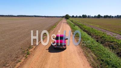 A Red Pickup Truck Traveling On A Dirt Road In A Rural Farm Area Of Mississippi - Aerial Video By Drone