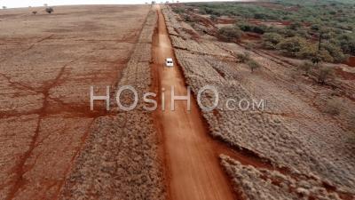 White Panel Van Police Transport Vehicle Traveling On A Generic Rural Dirt Road On Molokai, Hawaii From Maunaloa To Hale O Lono - Aerial Video By Drone