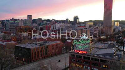 Aerial Past Portland Oregon Stag Deer Sign And Downtown Old Town Cityscape And Business District At Sunset Or Dusk. - Video Drone Footage