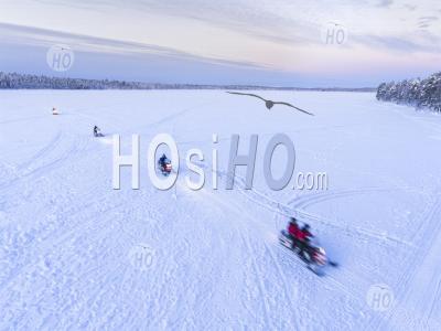 Aerial Drone Photo Of Snow Mobiles On A Snowmobiling Adventure On A Snow Covered Lake In Winter At Finnish Lapland, Finland