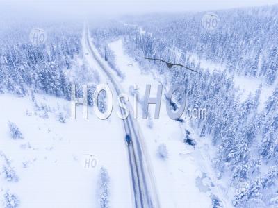 Aerial Of Car Driving On A Dangerous Winter Road In Bad Icy Conditions Next To Frozen River And Snow Covered Forest - Aerial Photography