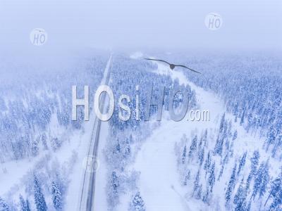 Vue Aérienne De La Route D'hiver Par Rivière Gelée Et Paysage Forestier Couvert De Neige Montrant Des Paysages De Laponie En Scandinavie En Finlande - Photographie Aérienne