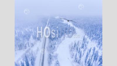Aerial Of Winter Road By Frozen River And Snow Covered Forest Landscape Showing Lapland Scenery In Scandinavia In Finland - Aerial Photography