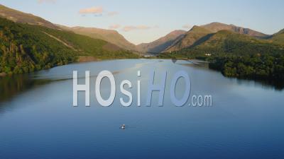 Lone Kayaker Kayaking On Calm Water Surface Of Llyn Padarn Lake In Wales, Aerial Shot Of Peaceful, Tranquil Outdoor Adventure In The Mountains Of Snowdonia - Video Drone Footage