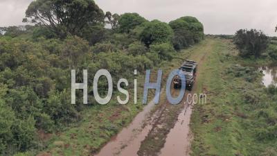 4 Wheel Drive Vehicle Driving Through Muddy Puddle In Aberdare National Park, Kenya, Africa. Aerial Drone On Safari