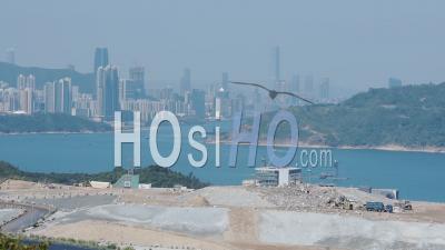 A Wide Landfill Area Next To The Coastline Of South China Overlooking The Skyline. -Wide Shot