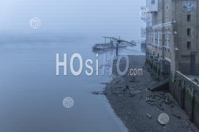 Butlers Wharf Pier At Low Tide With A River Thames Beach In Thick Foggy And Misty Moody Weather In London City Centre During Covid-19 Coronavirus Lockdown, England, Uk