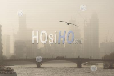 Atmospheric City In Orange Misty And Foggy Sunset With Central London City Skyline, Iconic Red London Bus Driving Over Lambeth Bridge And Skyscrapers And Offices, Shot In Coronavirus Covid-19 Lockdown In England, Uk