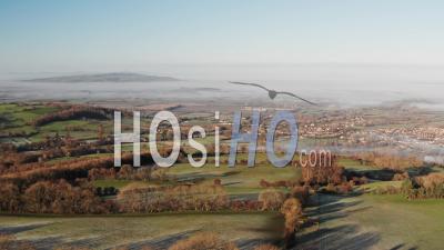 Aerial Drone View Of The Cotswolds Hills With Broadway In The Valley, With Beautiful Rural Countryside Views, Misty Green Fields And English Landscape Scenery In Mist In Gloucestershire, England, United Kingdom