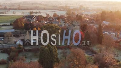 Aerial Drone Video Of Typical English Village And Beautiful British Countryside Scenery In The Cotswolds Showing A Rural Church At Sunrise In Morning Sun At Longborough, Gloucestershire, England, United Kingdom