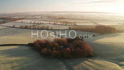 Aerial Drone Video Of Rural Countryside Landscape Scenery With Orange Autumn Trees And Green Fields In Farmland On A Farm With Typical Beautiful English Woods In The Cotswolds In Beautiful Sunrise Sunlight, England, United Kingdom