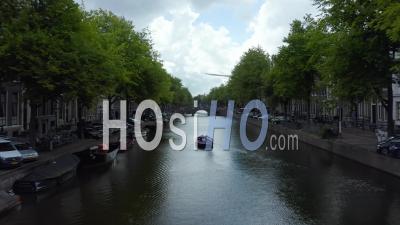 Canal D'amsterdam Avec Bateau Et Drapeau Néerlandais Agitant Dans Le Vent, Avant 4k - Séquence Vidéo Par Drone