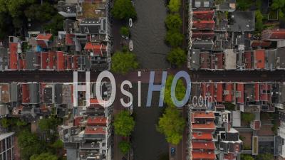 Amsterdam, Netherlands Canal Overhead Birds View With Boat Traffic And Red House Rooftops 4k - Video Drone Footage