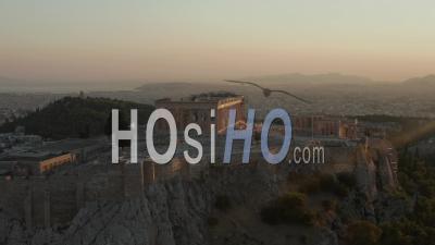 Aerial Flight Towards Acropolis Of Athens With Greek Flag Waving In Beautiful Golden Hour Sunset Light With Ocean In The Distance 4k - Video Drone Footage