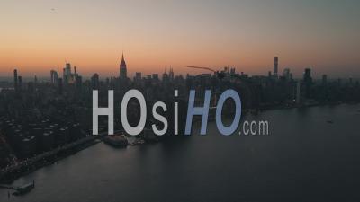 Over East River Showing Manhattan New York City Skyline In Beautiful Dawn Sunset Orange Light Right Before Dark 4k - Video Drone Footage