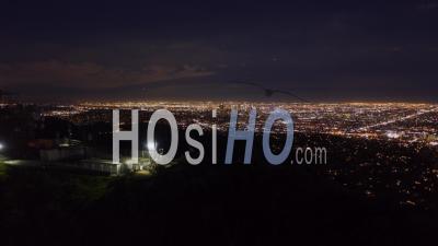 Aerial Hyper Lapse: Over Hollywood Sign At Night In Los Angeles, California At Night With Glowing Cityscape Time Lapse 4k - Video Drone Footage