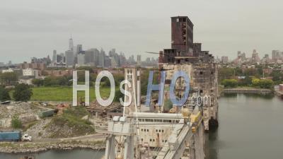 Aerial Ascending Pedestal View Of Truck Entering The Cargo Port With A Boat And Old Grain Terminal And New York City Skyline In The Background 4k - Video Drone Footage