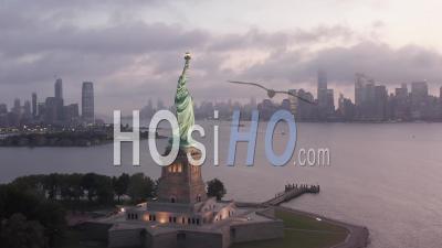 Circling Statue Of Liberty Illuminated In Early Morning Light With Foggy New York City Skyline In Background 4k - Video Drone Footage