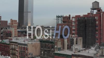 Aerial Dolly Shot Flying Low Above Rooftops Of Residential Buildings In Chinatown And Revealing Manhattan Bridge Towards Brooklyn In The Background 4k - Video Drone Footage