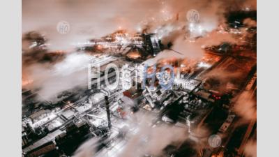 Aerial View Of Steel Plant At Night With Smokestacks And Fire Blazing Out Of The Pipe. Industrial Panoramic Landmark With Blast Furnance Of Metallurgical Production. Concept Of Environmental Pollution - Aerial Photography