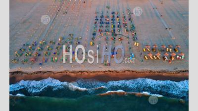 Sunset View Of A Sandy Mediterranean Beach With Colorful Sunbeds And Umbrellas. - Aerial Photography