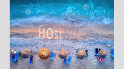 Vertical View Of Reed Umbrellas On Pebble Beach, Azure Sea And Surf. - Aerial Photography