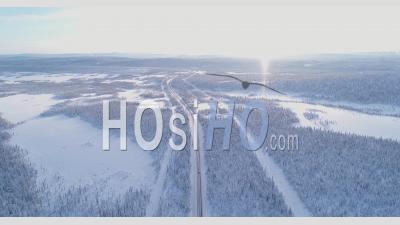 Vue Aérienne Montre Une Voiture Roulant Sur Une Autoroute Enneigée Bordée D'arbres En Suède - Vidéo Par Drone