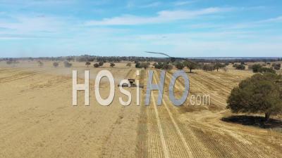 2020 - A Farming Combine Raising Dust And Cutting Through A Field In Parkes, New South Wales, Australia - Video Drone Footage