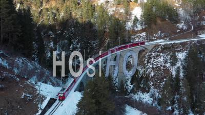 2022 - Excellent Aerial View Of A Train Traveling Across Bridge A Snowy Mountain Region Of Switzerland - Video Drone Footage