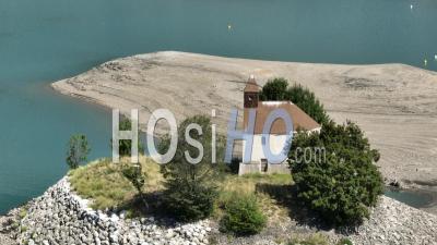 Prunières, Lac De Serre-Ponçon Sur La Durance, Drainage Du Lac, Sur L'îlot Saint-Michel La Chapelle Saint-Michel Du Xiie Siècle, Hautes-Alpes, France - Vidéo Par Drone
