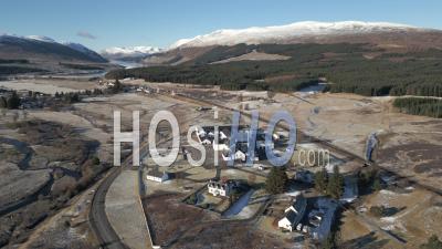 Dalwhinnie Distillery And Dalwhinnie Town With Ben Alder And Loch Ericht In The Background - Video Drone Footage