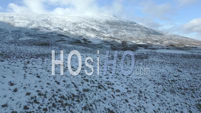 Snow-Capped Mountains During Winter Under Dappled Shade And Sun In The Scottish Highlands - Video Drone Footage