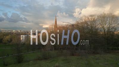 Queens Park And The Nearby Churches With A Rainbow During A Spring Afternoon With Tenement Housing, The City Centre And The Campsies Mountains In The Background - Video Drone Footage